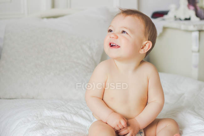 Rindo menino sentado na cama e olhando para cima — Fotografia de Stock