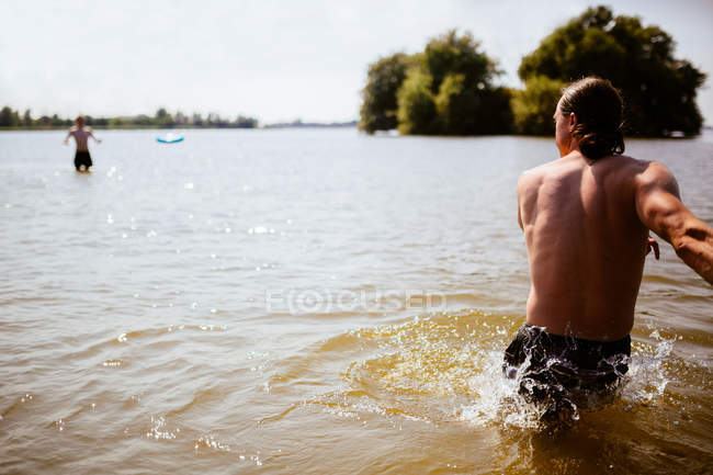 Man throwing plastic flying disc across lake, Ijsselmeer, The Netherlands — Stock Photo