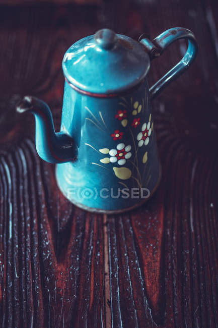 Elevated view of teapot with floral pattern on a wooden table — Stock Photo