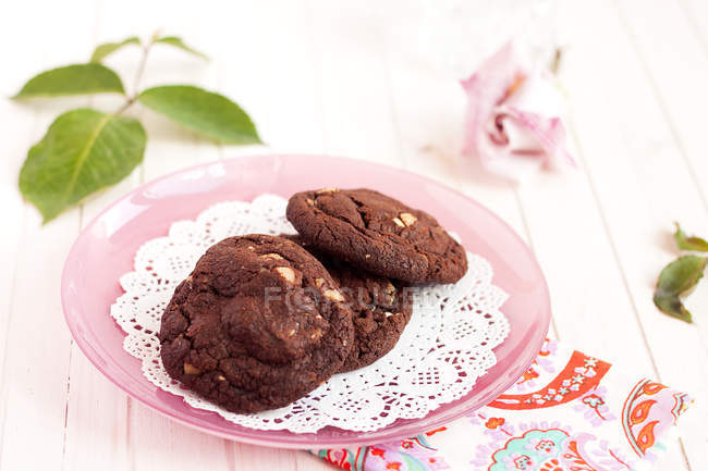 Три шоколадных печенья на розовой тарелке — стоковое фото