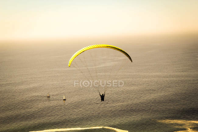 Parasail amarelo em voo na praia ao pôr do sol — Fotografia de Stock