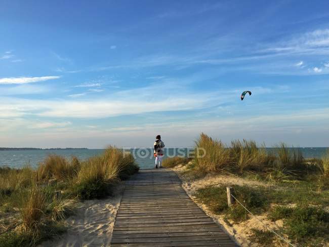 Rear view of a woman standing on the beach watching kiteboarder, La Rochelle, France — Stock Photo