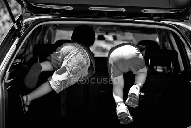 Вид сзади на двух маленьких мальчиков, играющих в задней части автомобиля — стоковое фото