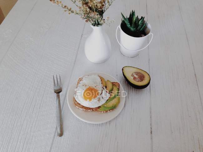 Aguacate y huevo frito en tostadas desayuno en mesa de madera - foto de stock
