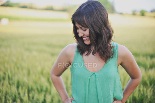 Jeune femme souriante debout dans le champ — Photo de stock