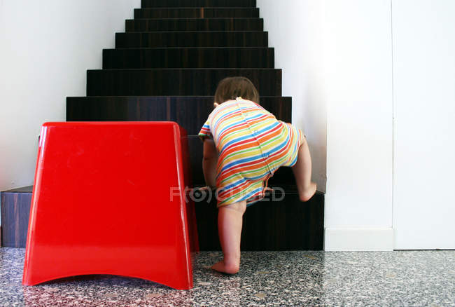 Rear view of Baby girl crawling up steps — Stock Photo
