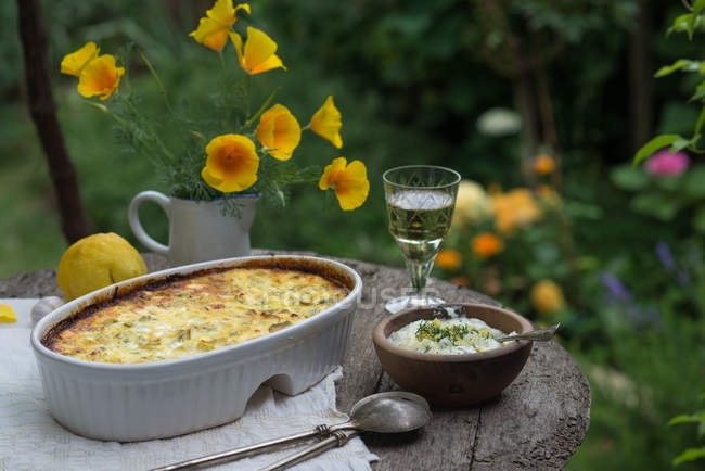 Bratkartoffeln und Käse auf Tisch im Freien mit Wein und Blumen — Stockfoto