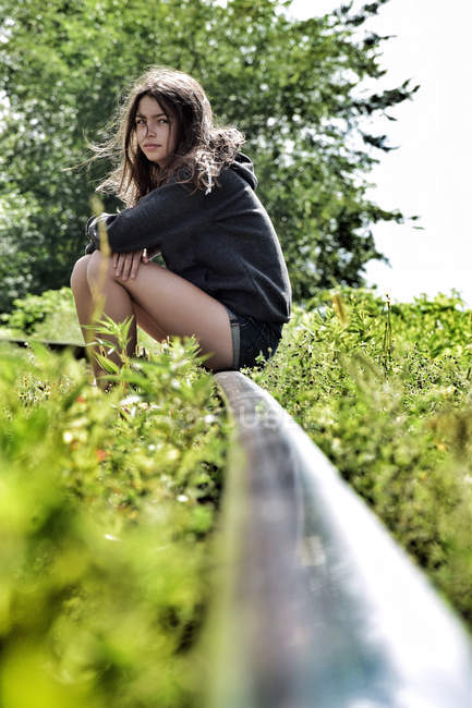 Chica sentada en la vía del tren en desuso en el campo - foto de stock