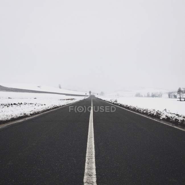 Vista panorámica de la carretera en la nieve, Solonghello, Piemont, Italia - foto de stock