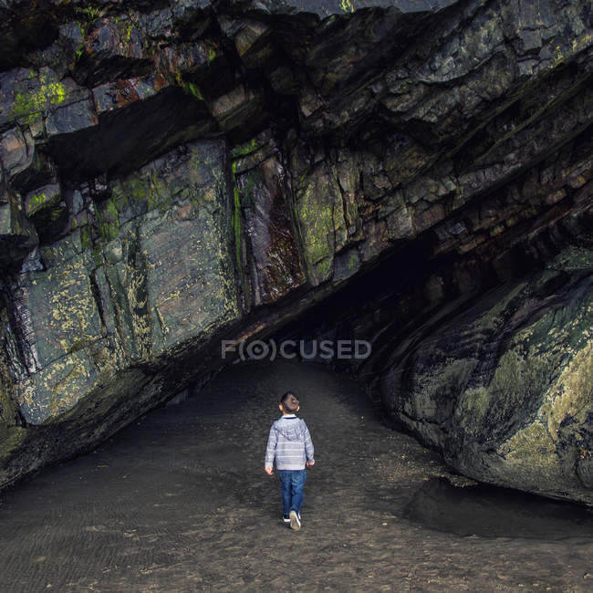 Vue arrière du petit garçon debout devant le tunnel rocheux — Photo de stock