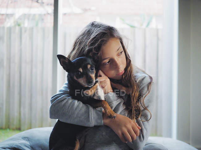 Chica abrazando perro Chihuahua y mirando hacia los lados - foto de stock
