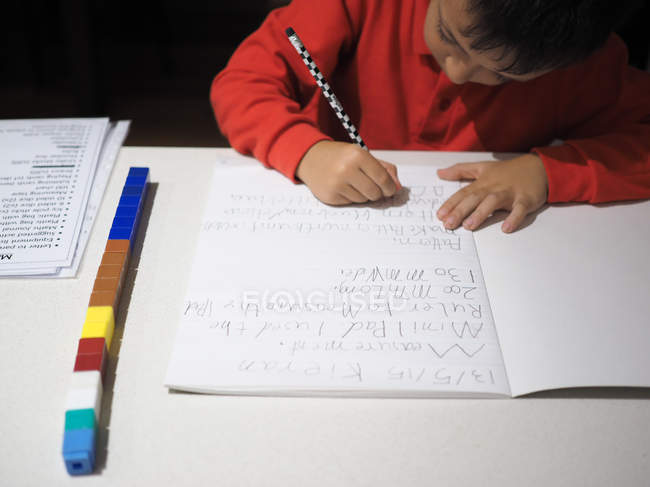 Rapaz a fazer trabalhos de casa de matemática na secretária — Fotografia de Stock