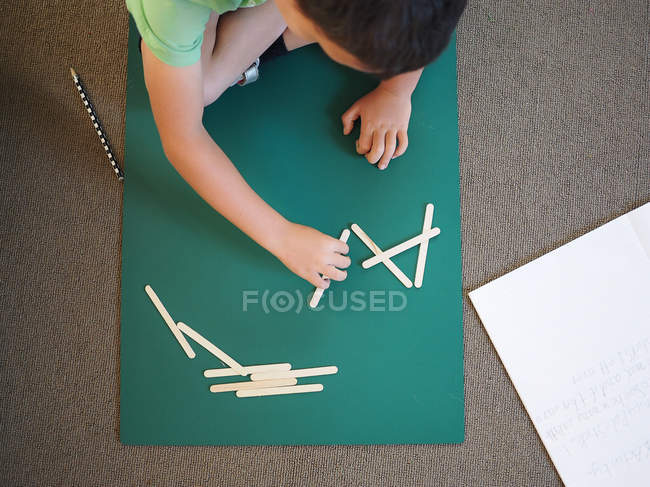 Garçon faisant des mathématiques de l'école primaire avec des bâtons — Photo de stock