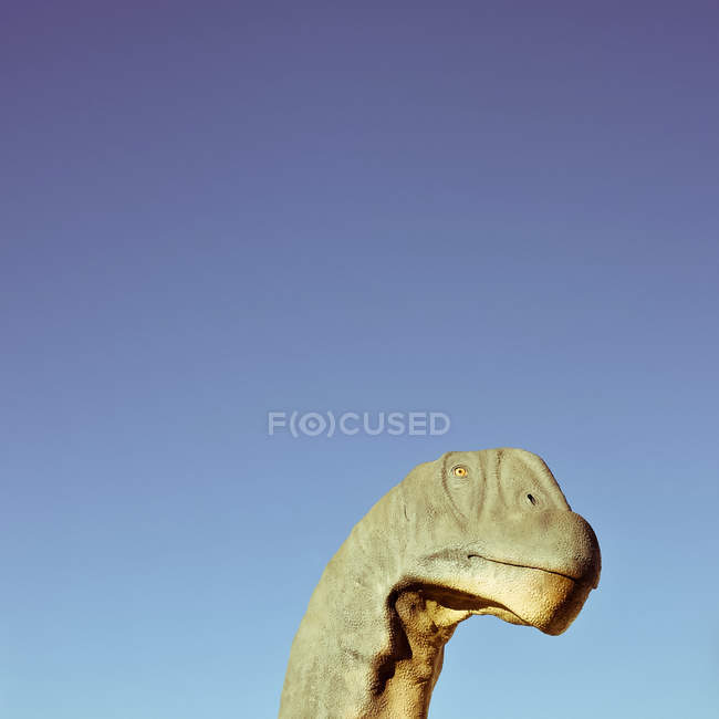Cabeça de dinossauro contra céu azul claro — Fotografia de Stock