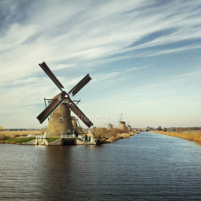 Vista panorâmica do moinho de vento por rio, paisagem idílica — Fotografia de Stock