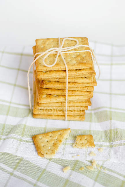 Stack of wholewheat crackers tied with rope on kitchen towel — Stock Photo