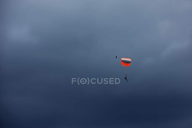 Man paragliding mid air in cloudy sky — Stock Photo