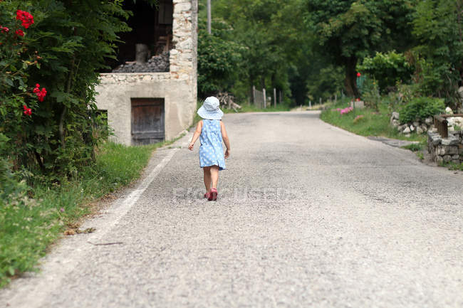 Вид сзади на девушку, идущую по горной дороге — стоковое фото