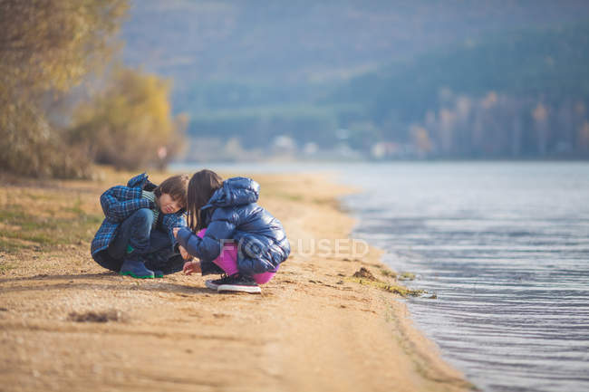 Brother and sister sitting on beach and playing — Stock Photo