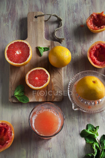 Naranjas de sangre y jugo exprimido en vidrio sobre superficie de madera - foto de stock