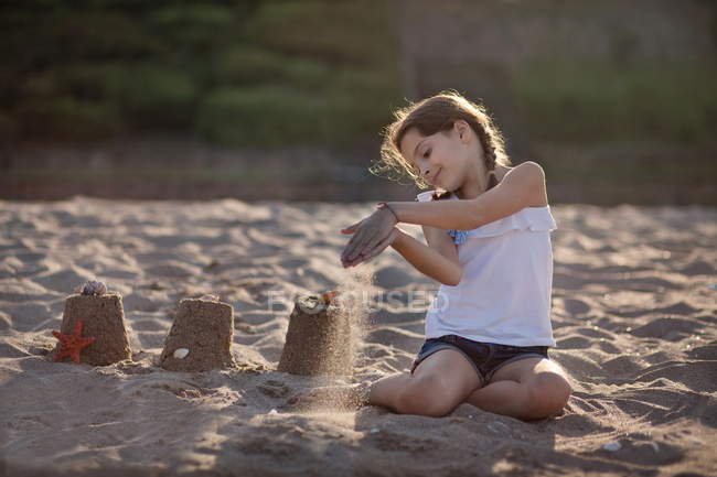 Улыбающаяся девочка, играющая на песчаном пляже — стоковое фото
