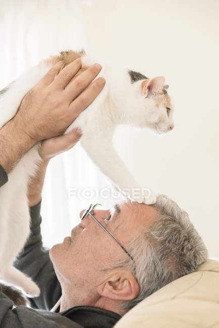 Nahaufnahme eines Mannes, der mit Katze spielt und liegt — Stockfoto