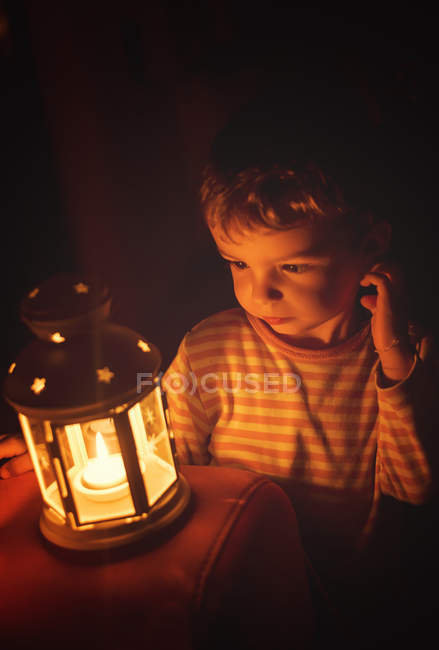 Menino olhando para vela noturna iluminada — Fotografia de Stock