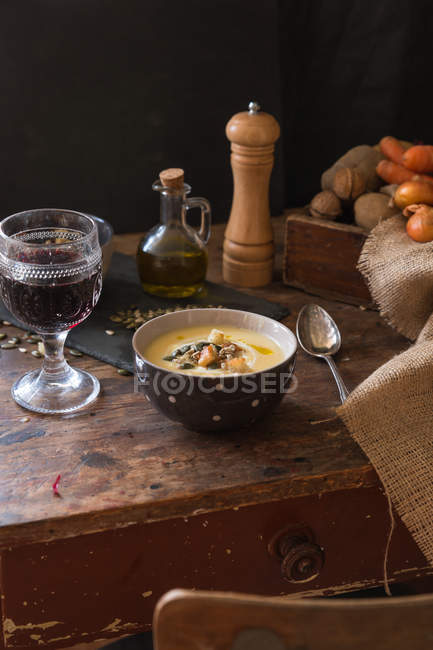 Ciotola di zuppa di patate con bicchiere di vino rosso — Foto stock