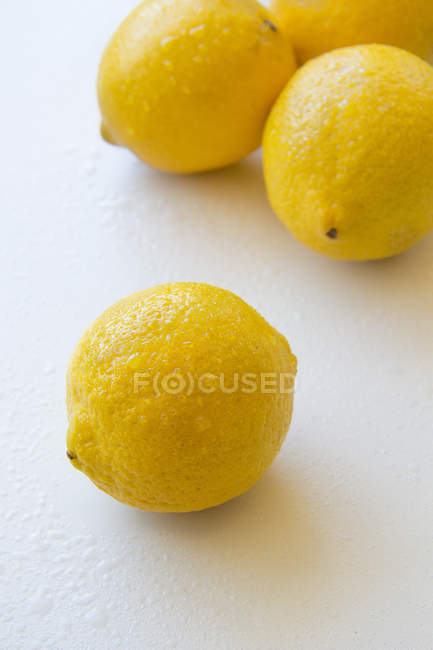 Wet lemons lying on white table, closeup — Stock Photo