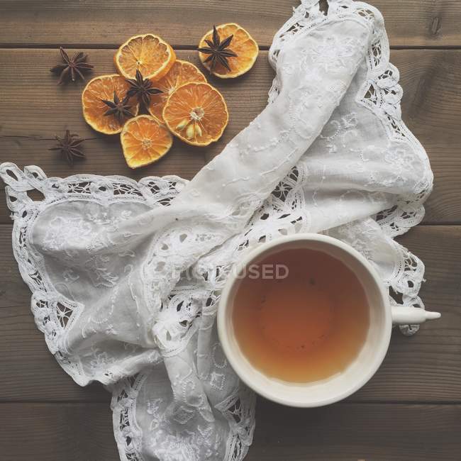 Tea and dried oranges in towel over wooden table — Stock Photo