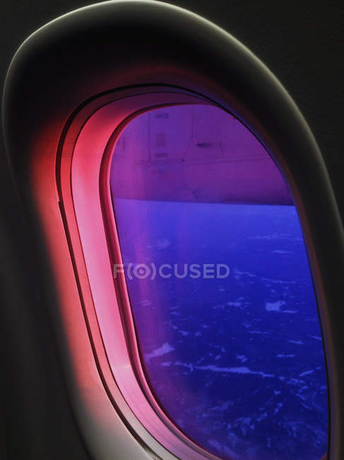 Vue à travers la fenêtre de l'avion au coucher du soleil — Photo de stock