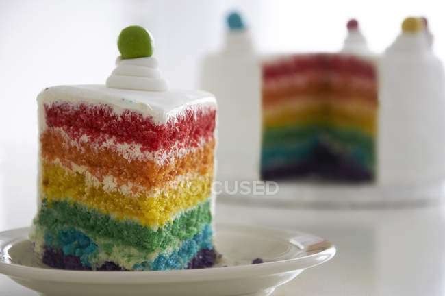 Primer plano de rebanada de pastel de arco iris en un plato - foto de stock