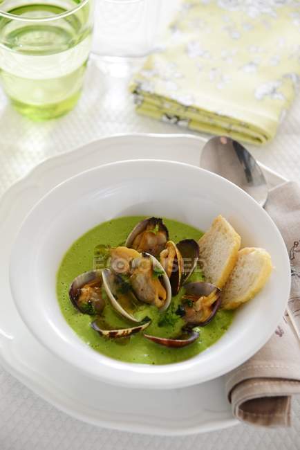 Tasty green pea soup with clams in bowl — Stock Photo