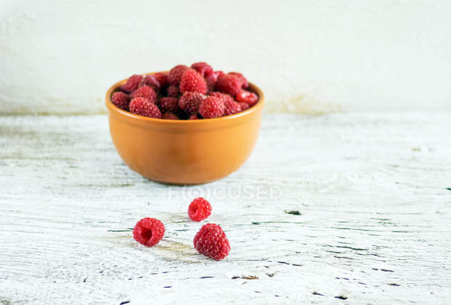 Bowl of fresh raspberries on wooden table — Stock Photo