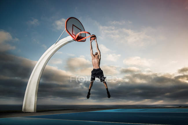 Молодий чоловік грає в баскетбол у парку — стокове фото