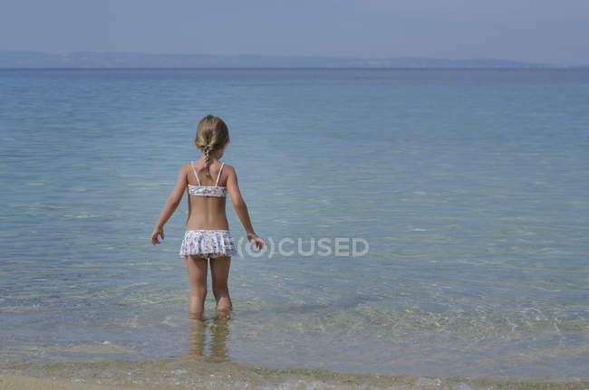 Little Girl wearing swimsuit walking into sea — Stock Photo