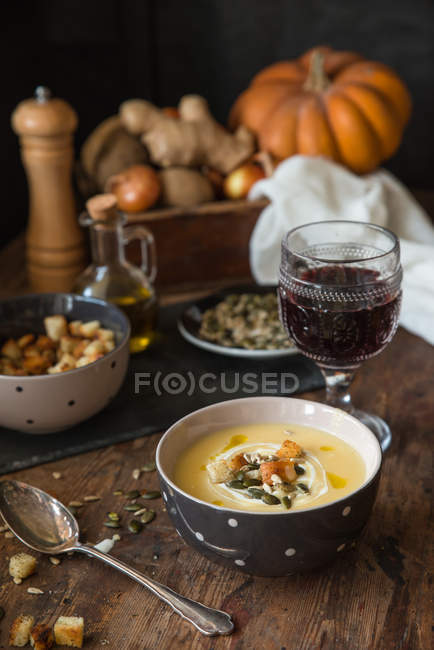 Potato soup with cream and glass of red wine in vintage designs — Stock Photo
