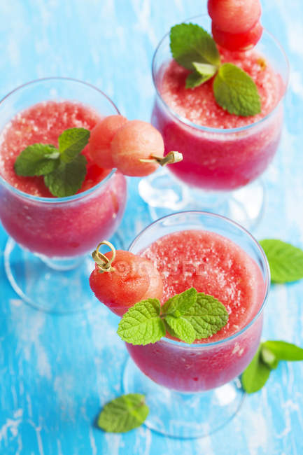 Three tasty watermelon smoothies over blue table — Stock Photo