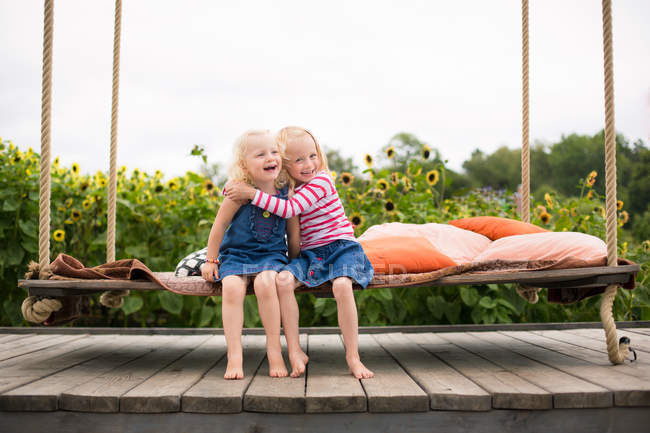 Deux jolies soeurs étreignant sur swing — Photo de stock