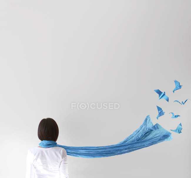 Visão traseira da mulher com cachecol azul e pássaros origami no fundo branco — Fotografia de Stock