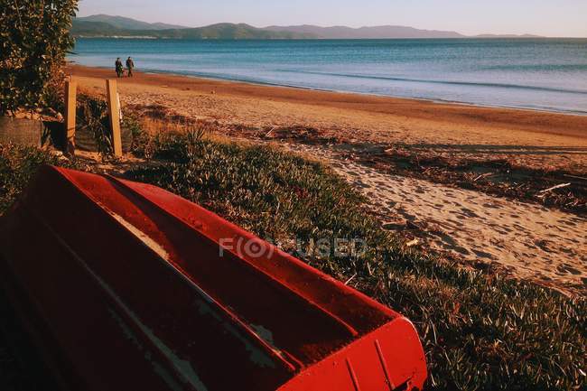 Мальовничий вид на червоний човен на пляжі на сході сонця — стокове фото