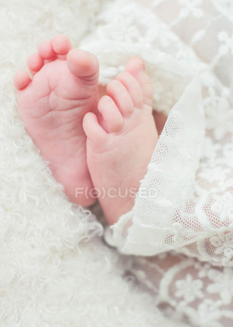 Primer plano de los pies de las niñas del bebé envuelto en tela de encaje - foto de stock