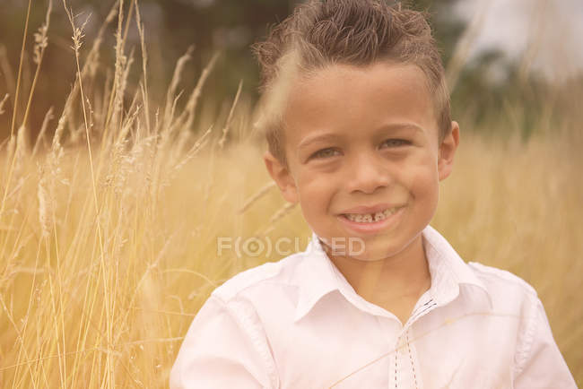 Портрет улыбающегося мальчика, стоящего на пшеничном поле — стоковое фото