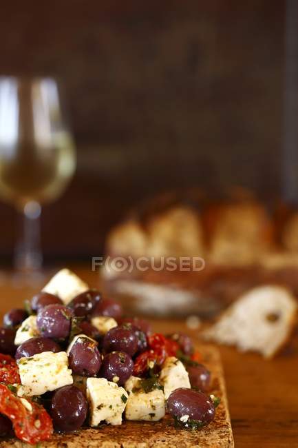 Olives brunes et fromage feta sur planche à découper — Photo de stock