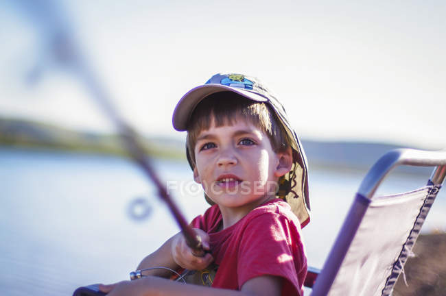 Garçon assis dans la chaise à l'extérieur et la pêche — Photo de stock