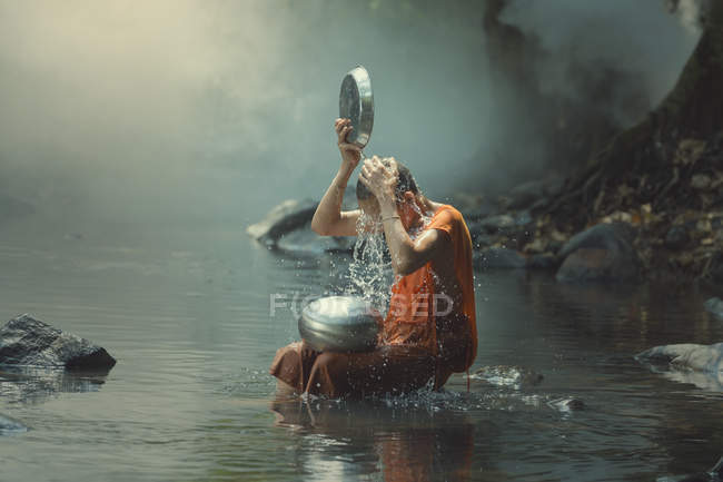 Novice monk cooling off in a creek, Asia — Stock Photo