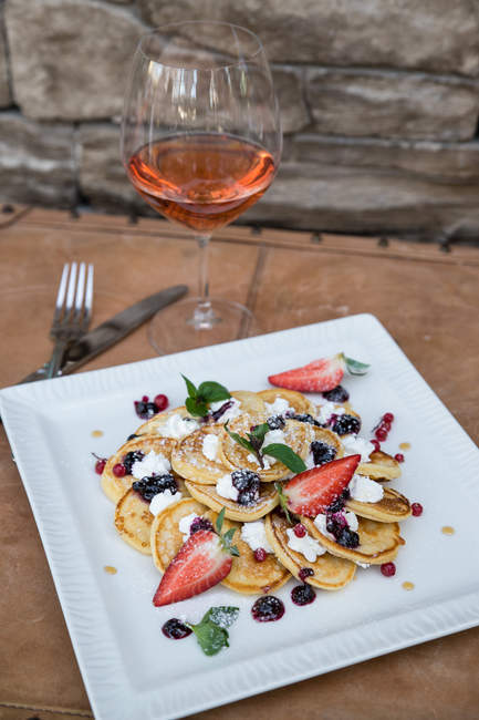 Sweet pancakes in white plate with rose wine — Stock Photo