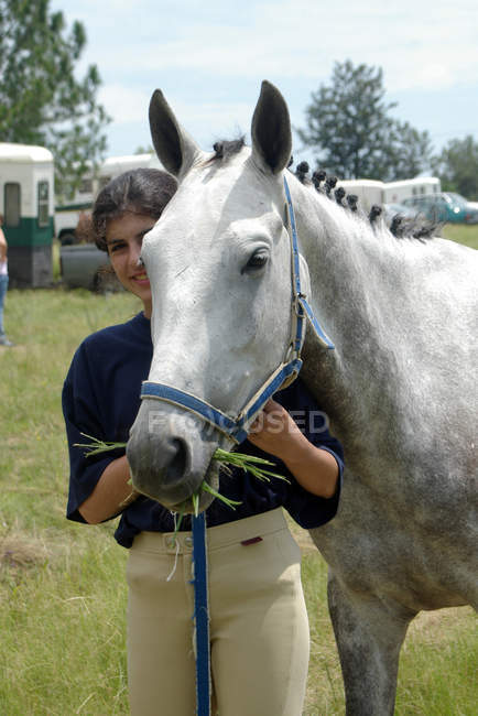 Teenage girl standing with horse at show jumping competition — Stock Photo