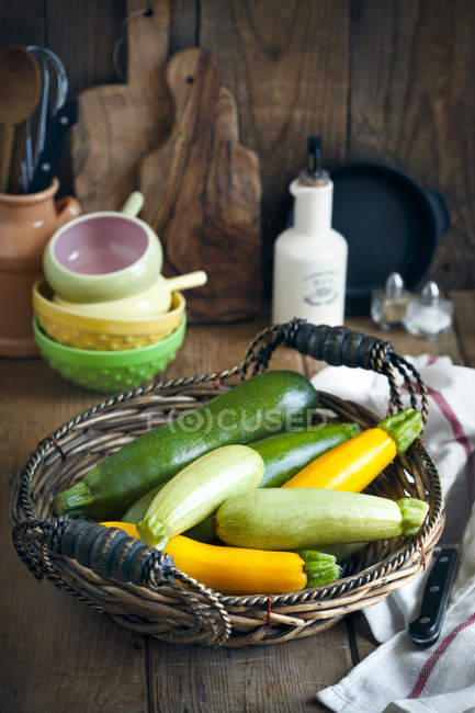 Abobrinha fresca na cesta na mesa de madeira — Fotografia de Stock