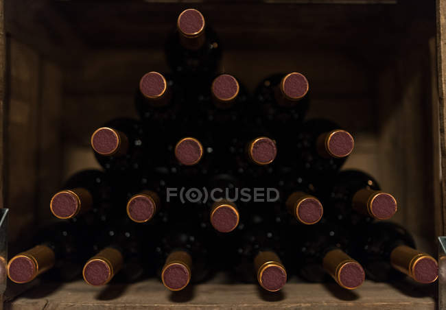 Stack of red wine bottles on shelf — Stock Photo